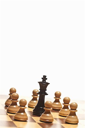 Pions blancs entourant le roi noir d'échecs Photographie de stock - Premium Libres de Droits, Code: 649-05951269