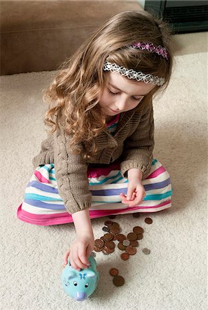 saving for a rainy day - Girl putting coins in piggy bank Stock Photo - Premium Royalty-Free, Code: 649-06000332