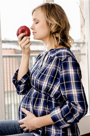 responsibility - Smiling pregnant woman smelling apple Stock Photo - Premium Royalty-Free, Code: 649-06000424