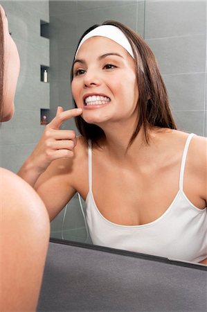 Woman examining her teeth in mirror Stock Photo - Premium Royalty-Free, Code: 649-06000646