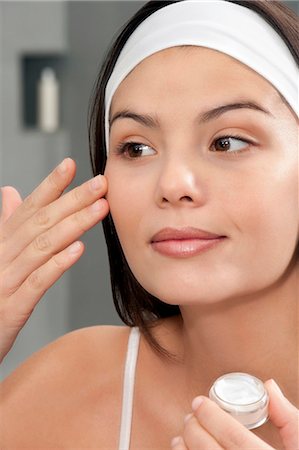 Woman applying moisturizer in mirror Foto de stock - Royalty Free Premium, Número: 649-06000640