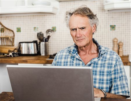 simsearch:649-06000711,k - Older man using laptop in kitchen Foto de stock - Sin royalties Premium, Código: 649-06000704