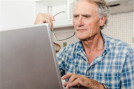 simsearch:6113-07906179,k - Older man using laptop in kitchen Stock Photo - Premium Royalty-Free, Code: 649-06000705