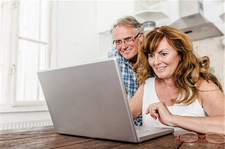 senior man looking up smiling - Older couple using laptop in kitchen Stock Photo - Premium Royalty-Free, Code: 649-06000710