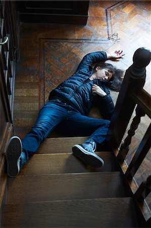 Teenage boy laying at foot of stairs Foto de stock - Royalty Free Premium, Número: 649-06000732