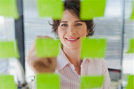 Businesswoman writing on sticky notes Stock Photo - Premium Royalty-Free, Code: 649-06000839