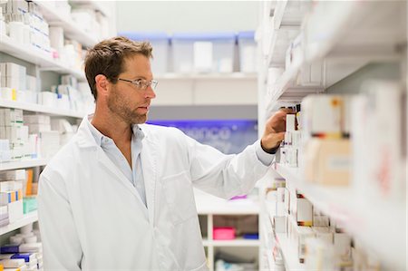 drugstore - Pharmacist browsing medicines on shelf Stock Photo - Premium Royalty-Free, Code: 649-06001014