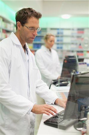 pharmacist (male) - Pharmacist using computer at counter Foto de stock - Sin royalties Premium, Código: 649-06001039