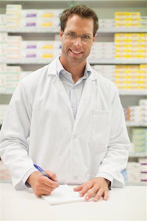 prescribed - Pharmacist making notes at counter Foto de stock - Sin royalties Premium, Código: 649-06001033