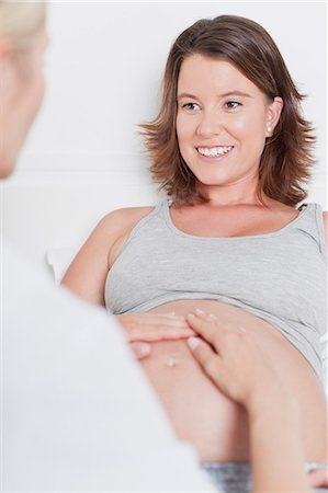 pregnant and doctor - Doctor examining pregnant womans belly Foto de stock - Sin royalties Premium, Código: 649-06001075