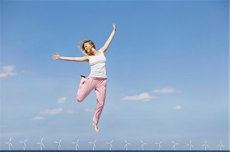 Woman jumping for joy over wind turbines Foto de stock - Sin royalties Premium, Código: 649-06001396