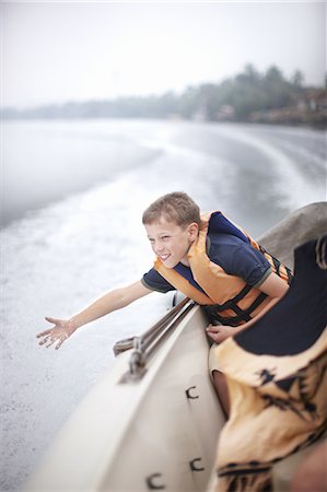 Teenage boy reaching to water from boat Stock Photo - Premium Royalty-Free, Code: 649-06001711