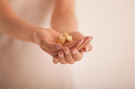 person cupping hands - Woman holding golden ornaments Stock Photo - Premium Royalty-Free, Code: 649-06040018