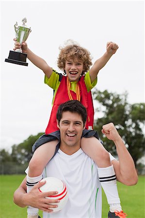exuberant - Coach carrying child with trophy Stock Photo - Premium Royalty-Free, Code: 649-06040326