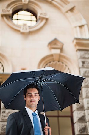 simsearch:649-06040493,k - Businessman carrying umbrella on street Stock Photo - Premium Royalty-Free, Code: 649-06040349