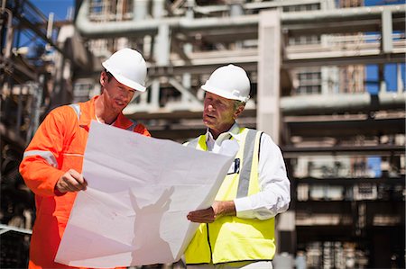 Workers with blueprints at oil refinery Stock Photo - Premium Royalty-Free, Code: 649-06040359