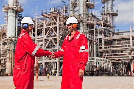 Workers shaking hands at oil refinery Stock Photo - Premium Royalty-Free, Code: 649-06040450