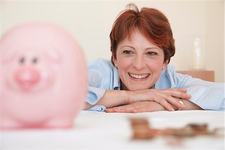 people saving money - Smiling woman admiring piggy bank Stock Photo - Premium Royalty-Free, Code: 649-06040952