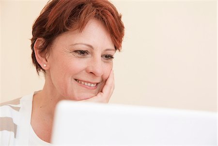 redhead woman 40s smiling - Smiling woman using laptop Stock Photo - Premium Royalty-Free, Code: 649-06040960