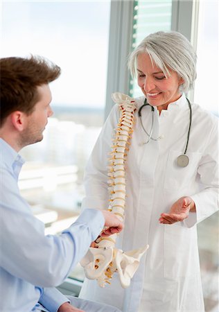 doctor advising patient in hospital - Doctor showing spine model to patient Stock Photo - Premium Royalty-Free, Code: 649-06041133