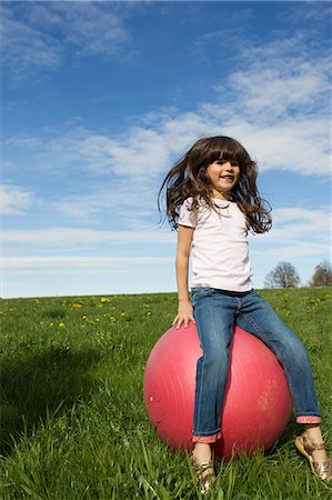 Girl playing on bouncy ball outdoors Stock Photo - Premium Royalty-Free, Code: 649-06112595