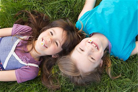 Smiling girls laying in grass together Stock Photo - Premium Royalty-Free, Code: 649-06112620