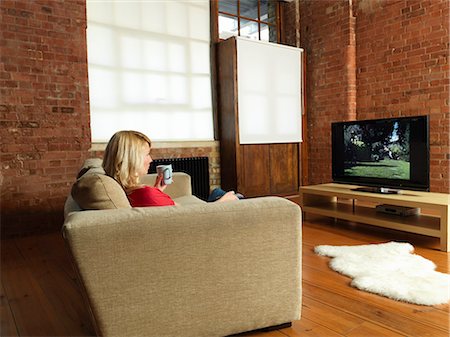 picture of someone watching television side view - Woman watching television on sofa Stock Photo - Premium Royalty-Free, Code: 649-06112711