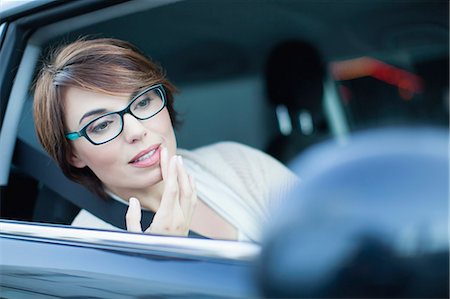 Woman checking makeup in side mirror Stock Photo - Premium Royalty-Free, Code: 649-06112804