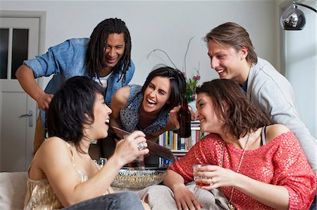 simsearch:649-06112949,k - Friends laughing together in living room Fotografie stock - Premium Royalty-Free, Codice: 649-06112960