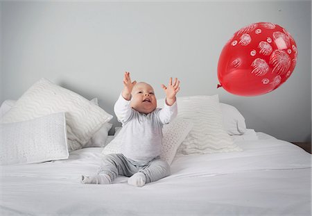 Baby boy playing with balloon on bed Fotografie stock - Premium Royalty-Free, Codice: 649-06113151