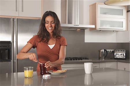 desayuno - Woman spreading jam on toast in kitchen Foto de stock - Sin royalties Premium, Código: 649-06113769