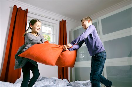 Children having pillow fight on bed Foto de stock - Sin royalties Premium, Código: 649-06113827