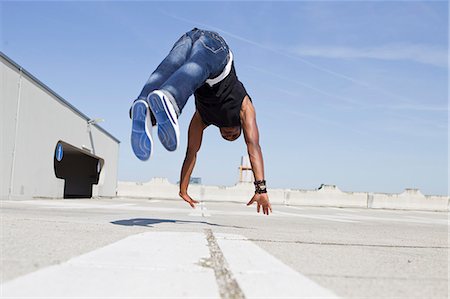 simsearch:649-06164470,k - Man jumping on rooftop Foto de stock - Sin royalties Premium, Código: 649-06164461