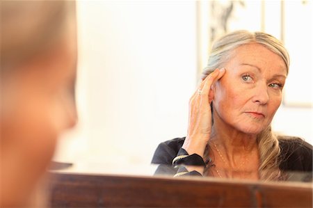 Older woman applying makeup in mirror Stock Photo - Premium Royalty-Free, Code: 649-06164509