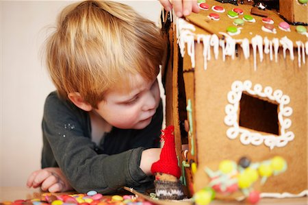 Boy decorating gingerbread house Fotografie stock - Premium Royalty-Free, Codice: 649-06164701