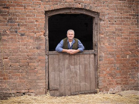 stable - Farmer standing at gate of barn Stock Photo - Premium Royalty-Free, Code: 649-06164967