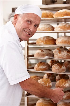 Chef putting tray of bread on rack Stock Photo - Premium Royalty-Free, Code: 649-06165049