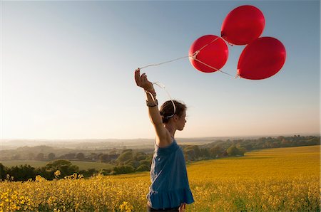 Girl carrying balloons in field Stock Photo - Premium Royalty-Free, Code: 649-06165188