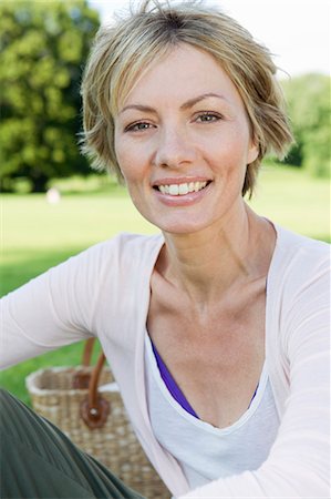 Femme souriante assise dans le parc Photographie de stock - Premium Libres de Droits, Code: 649-06305026