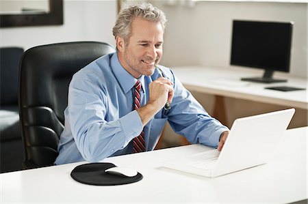simsearch:649-06305824,k - Businessman working on laptop at desk Foto de stock - Royalty Free Premium, Número: 649-06305234