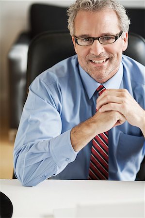 shirt businessman - Smiling businessman sitting at desk Stock Photo - Premium Royalty-Free, Code: 649-06305235