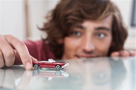 Teenage boy playing with toy car Stock Photo - Premium Royalty-Free, Code: 649-06305290