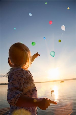 dock, sunset - Girl watching balloons floating away Stock Photo - Premium Royalty-Free, Code: 649-06305408