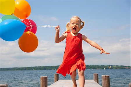 Girl holding balloons on wooden pier Stock Photo - Premium Royalty-Free, Code: 649-06305421