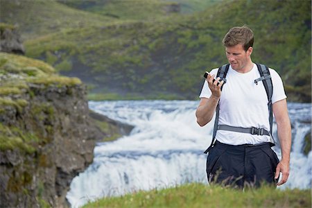 Hiker using cell phone on hillside Stock Photo - Premium Royalty-Free, Code: 649-06305447