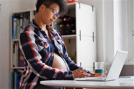 pregnant woman standing with computer - Pregnant woman using laptop in kitchen Stock Photo - Premium Royalty-Free, Code: 649-06305765