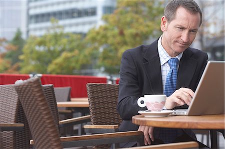 simsearch:6113-07543452,k - Businessman working on laptop at cafe Stock Photo - Premium Royalty-Free, Code: 649-06305945