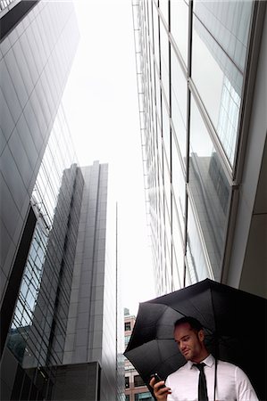 protection (protection against dangerous situations, substances or products) - Businessman walking under umbrella Foto de stock - Sin royalties Premium, Código: 649-06352706