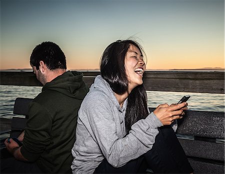 Couple à l'aide de téléphones cellulaires à l'extérieur Photographie de stock - Premium Libres de Droits, Code: 649-06352751