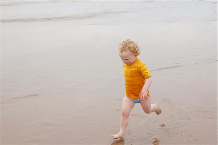 simsearch:649-06352470,k - Boy running in waves on beach Fotografie stock - Premium Royalty-Free, Codice: 649-06352911